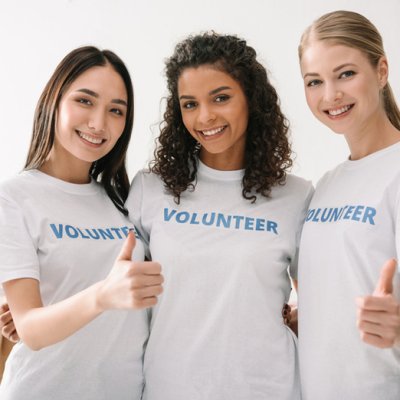 Three young women volunteers standing together and smiling at the camera.]